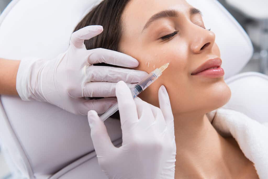 Happy lady on procedure of cheek zone in salon