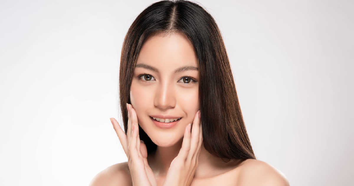Woman with radiant, smooth skin gently touching her face and smiling representing the results of a Chemical Peel in Northborough, MA.